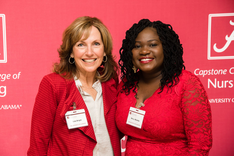Dr. Mercy Mumba poses with Lisa Bright, both wearing crimson red 